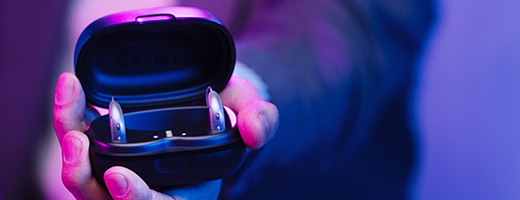 Image of hand holding open hearing aid case with Genesis AI standard hearing aids inside